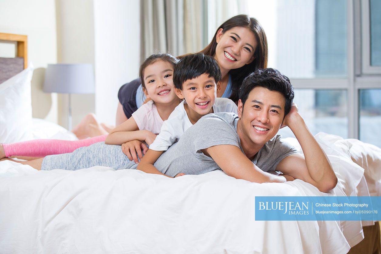 Cheerful young Chinese family on a bed