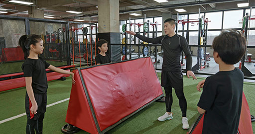 Active Chinese children having exercise class with their coach in gym,4K
