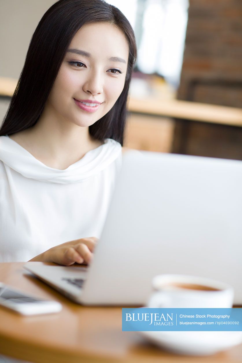 Young Chinese woman working with laptop in café
