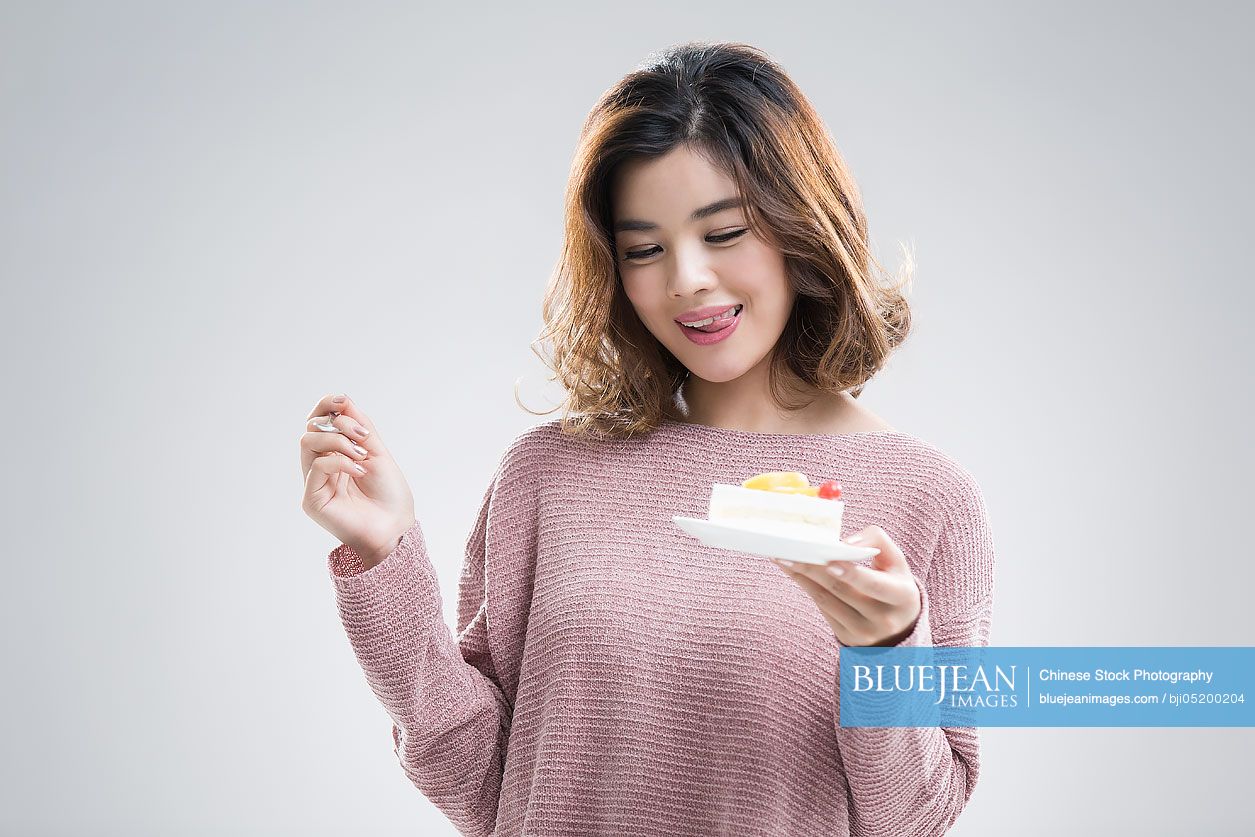 Beautiful young Chinese woman eating cake