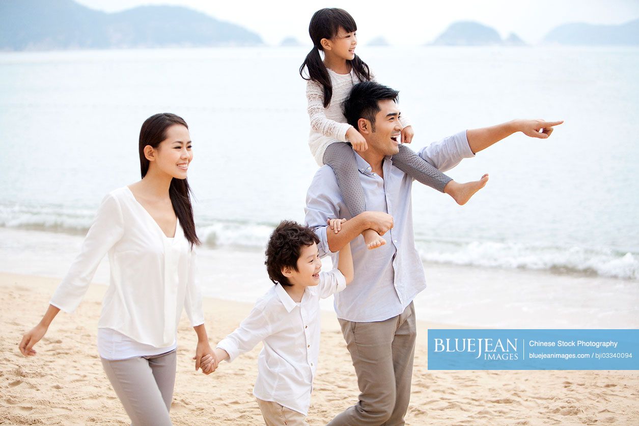 Happy young Chinese family strolling on the beach of Repulse Bay, Hong Kong