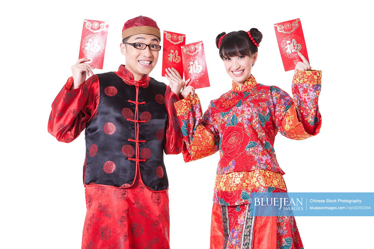 Young Chinese couple holding red pockets in traditional clothing