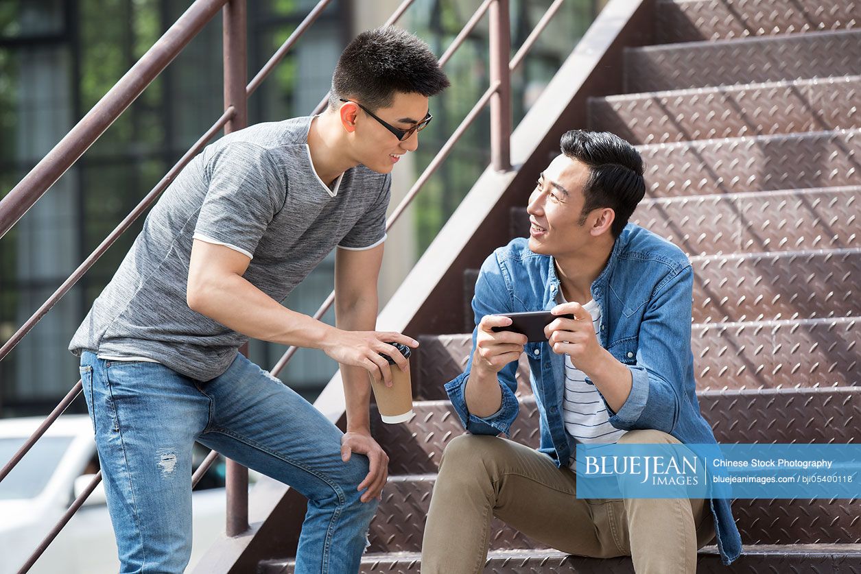 Young Chinese men having coffee break outdoors