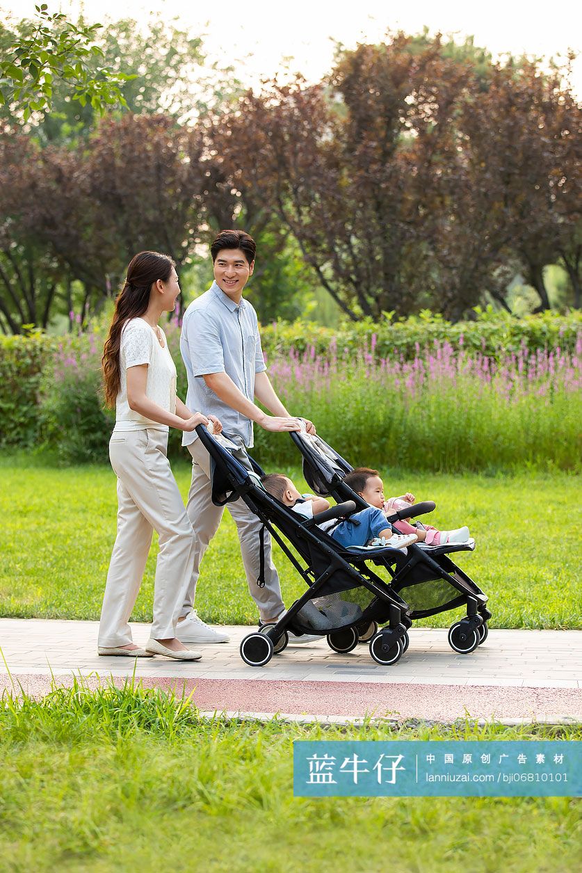 年轻父母带着龙凤胎宝宝在公园散步