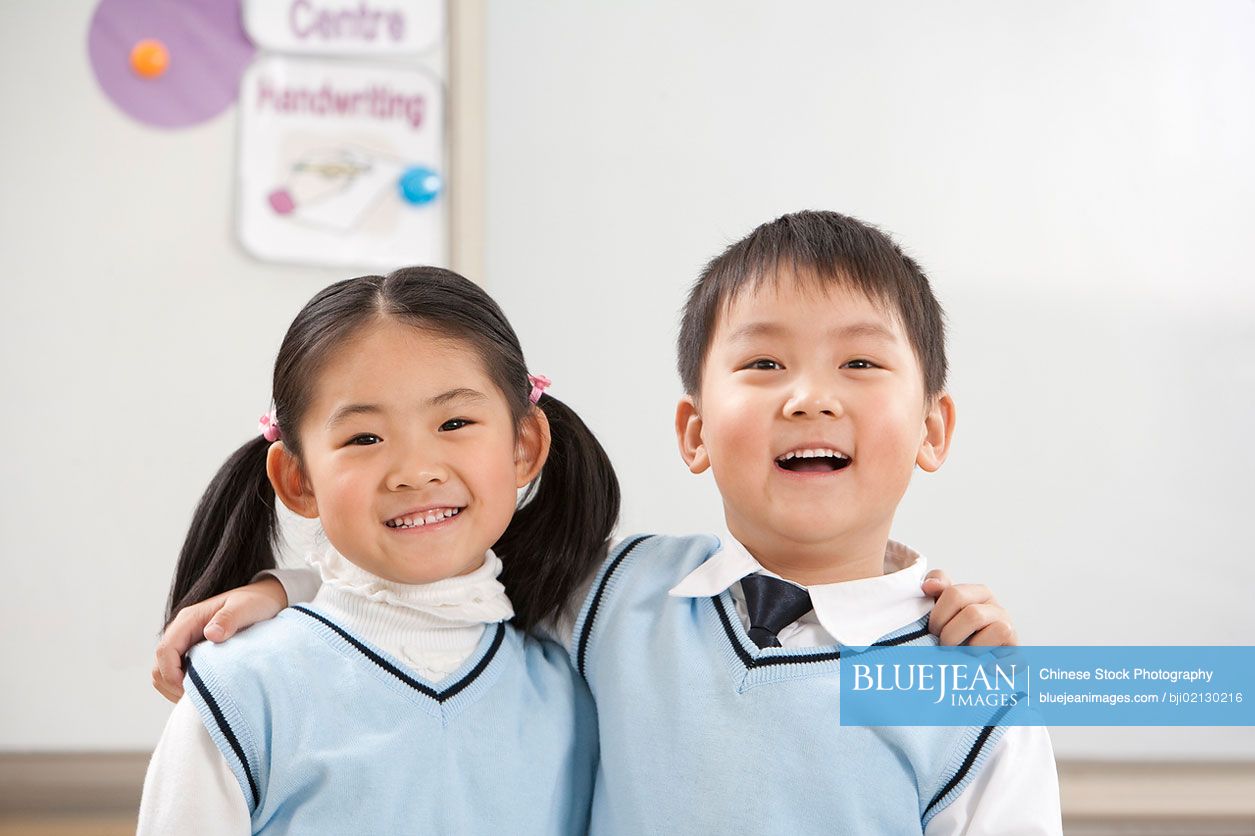 Chinese schoolboy and schoolgirl side by side smiling
