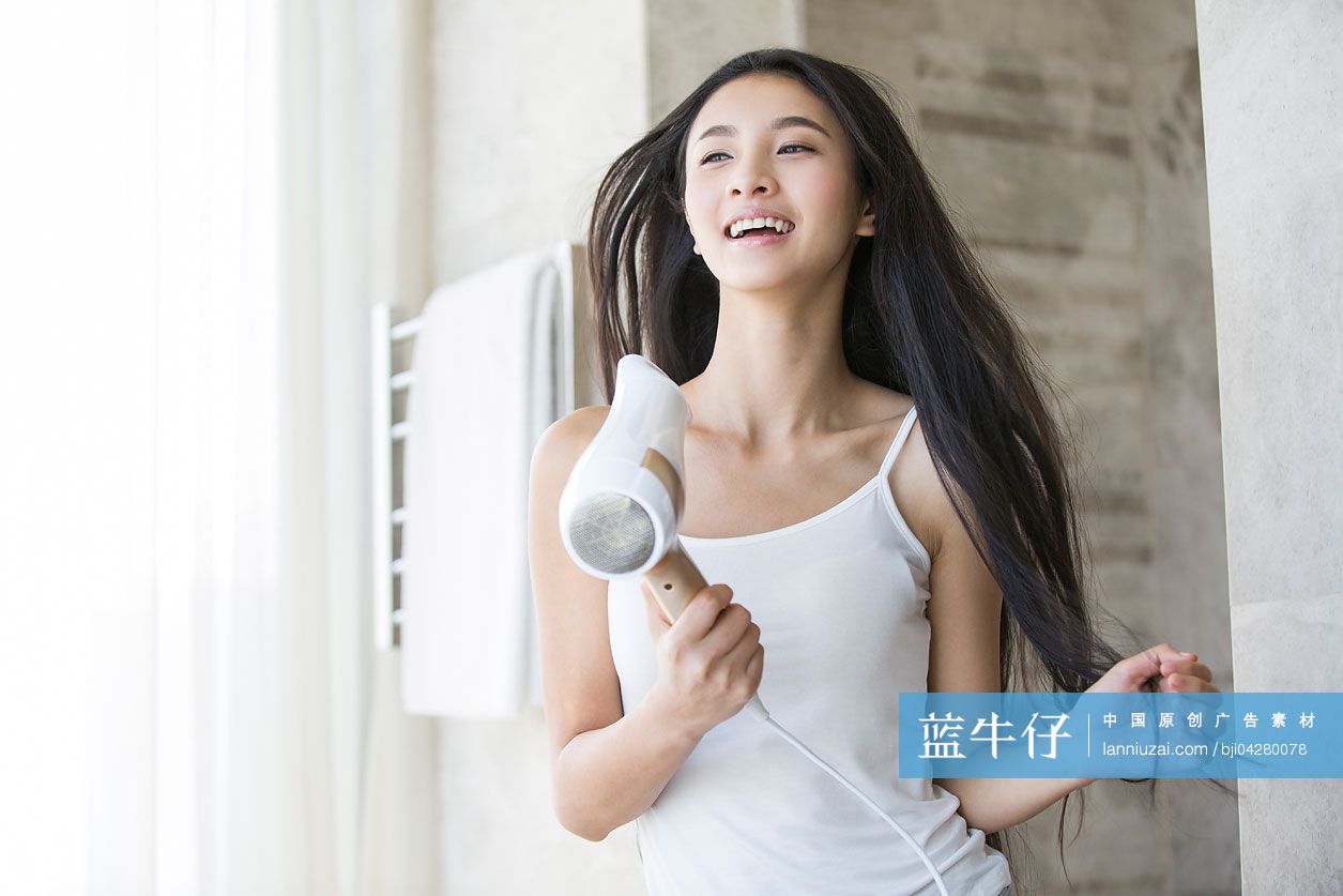 年轻女子用吹风机吹头发