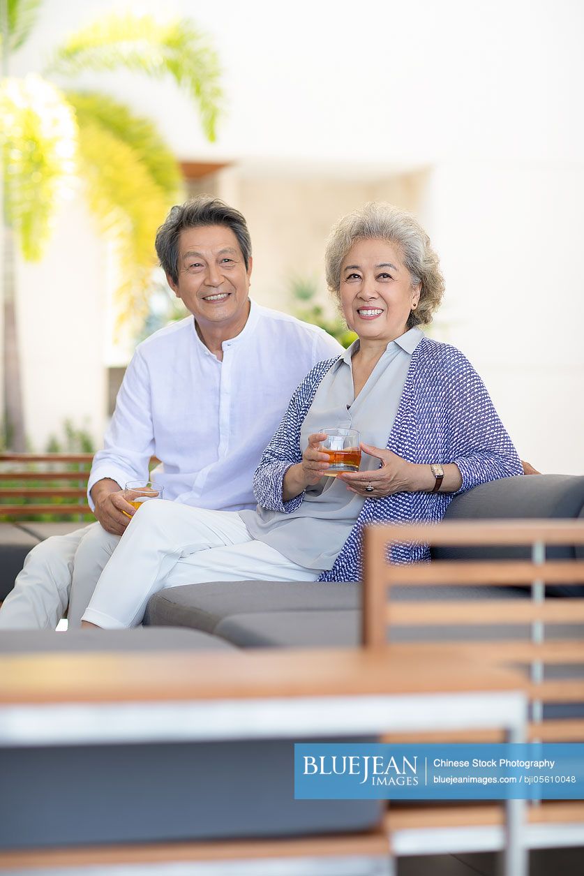 Happy senior Chinese couple relaxing on sofa