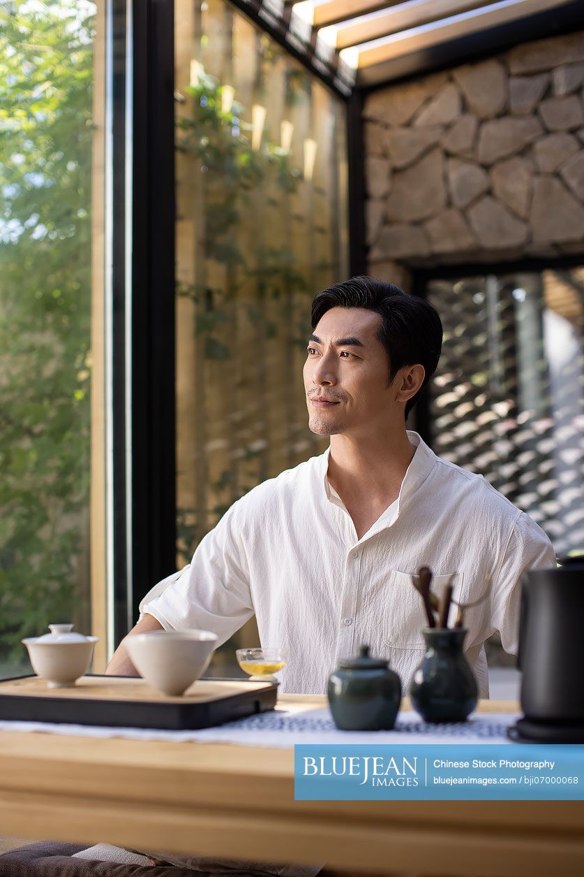 Mid adult Chinese man drinking tea in tea room