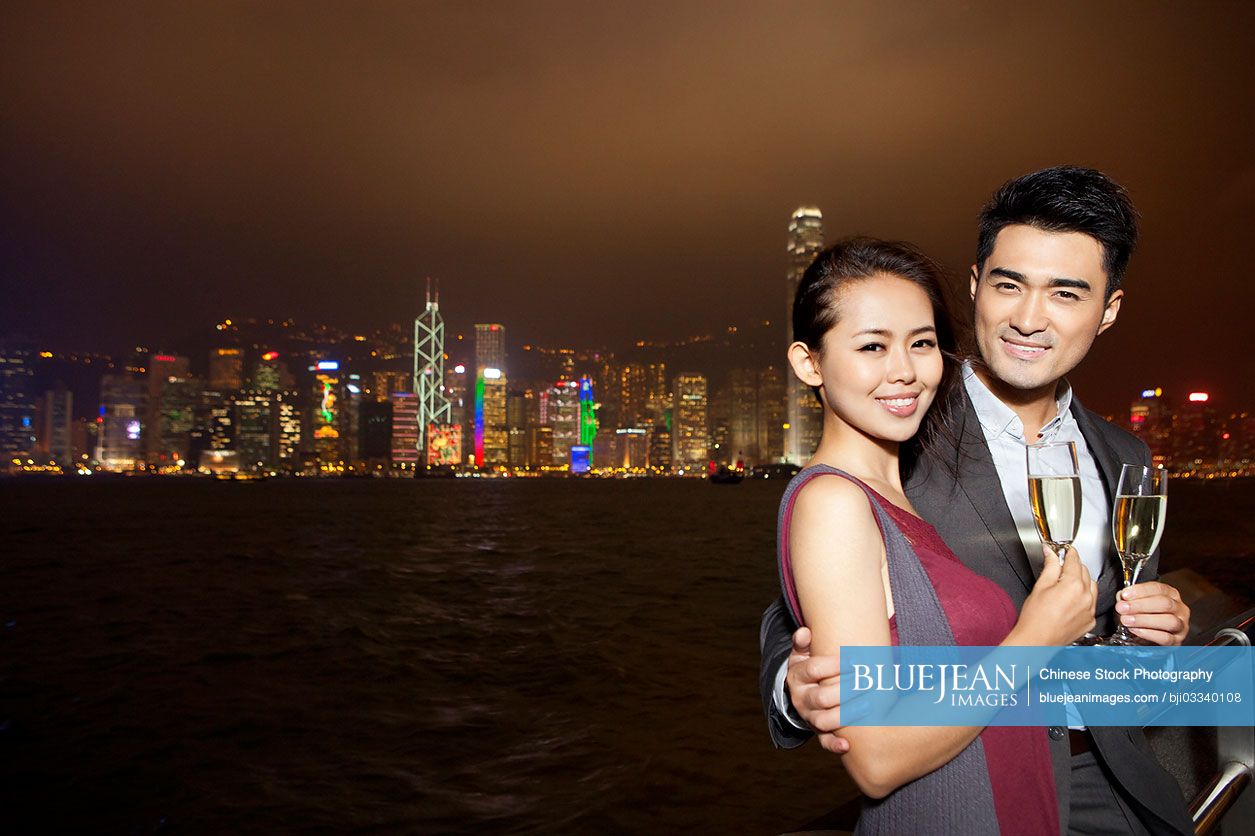 Happy young Chinese couple enjoying the night view of Victoria Harbor ...