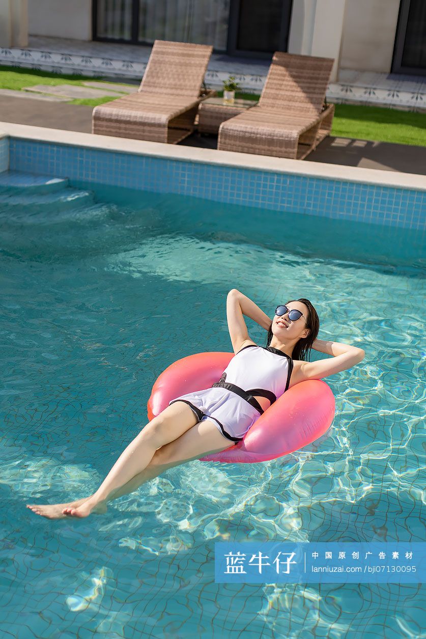 快乐的年轻女子在泳池里晒日光浴