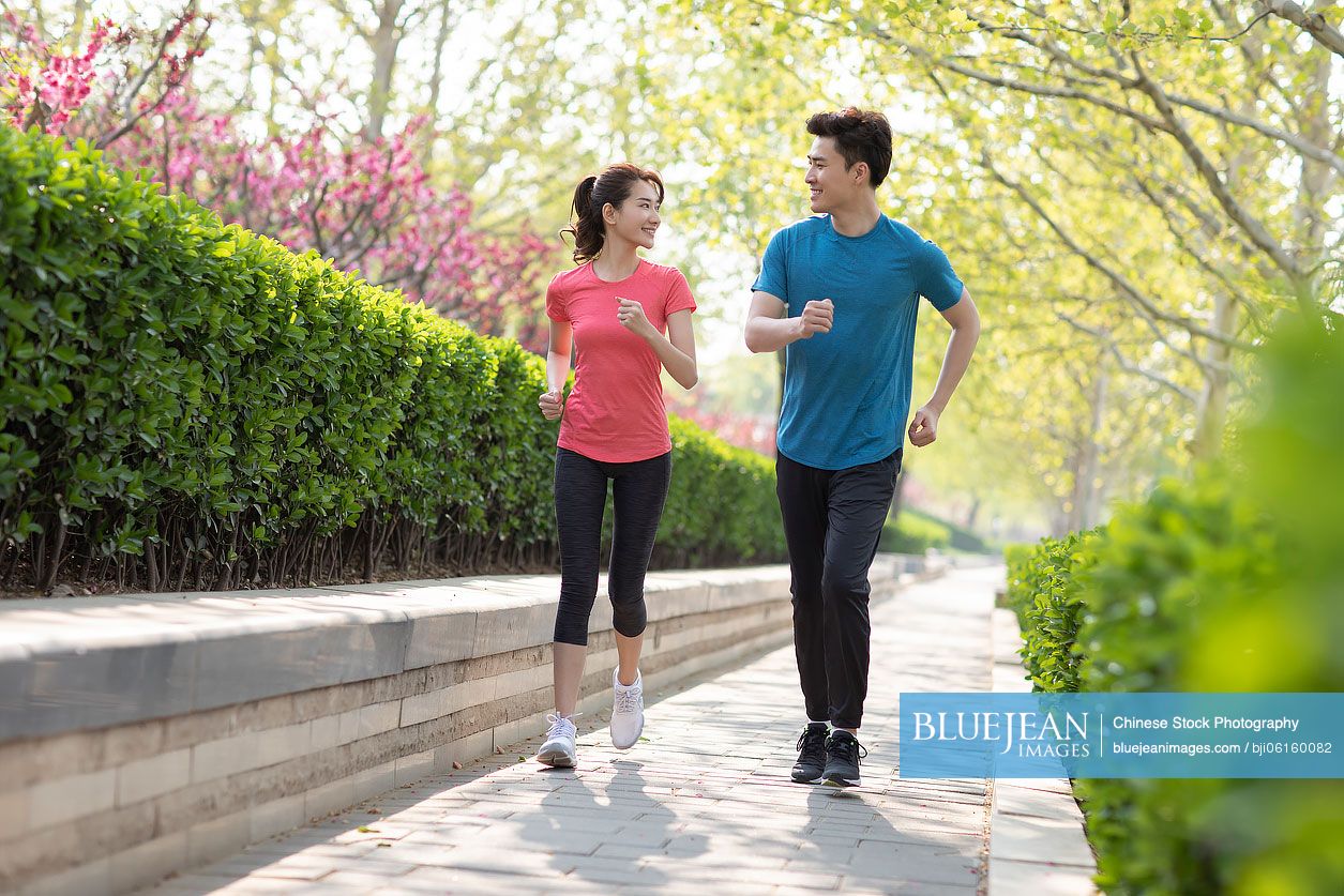 Happy young Chinese couple running in park