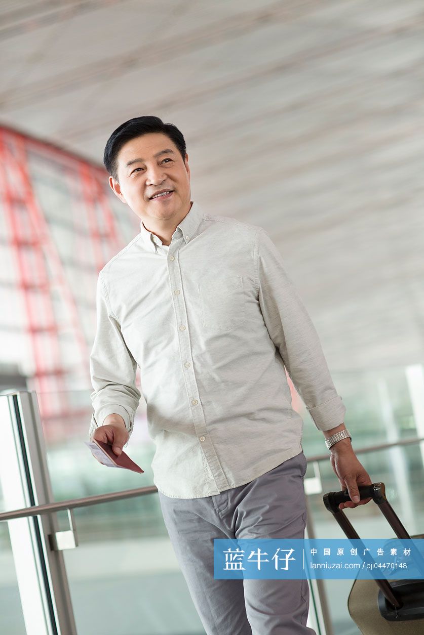 成熟中年男人拉着行李箱在机场走