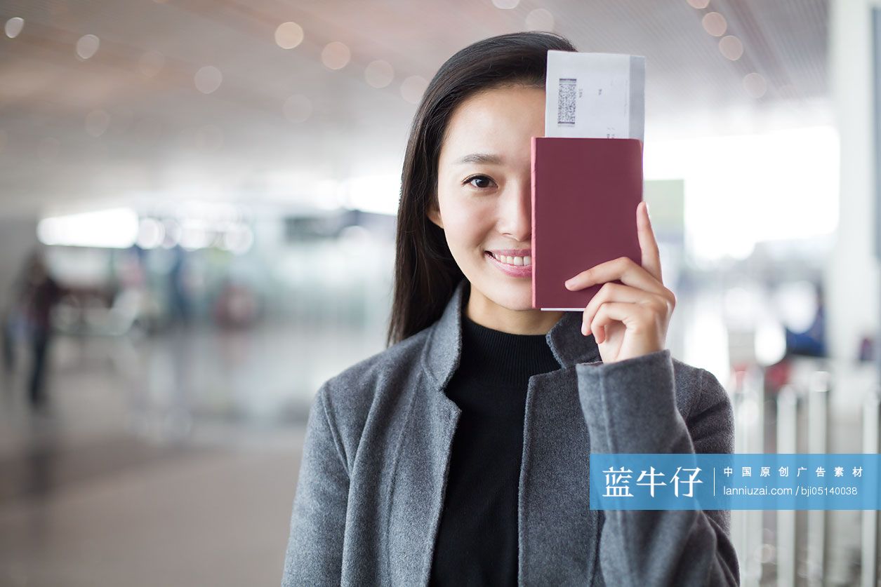 年轻商务女子在机场拿着机票和护照