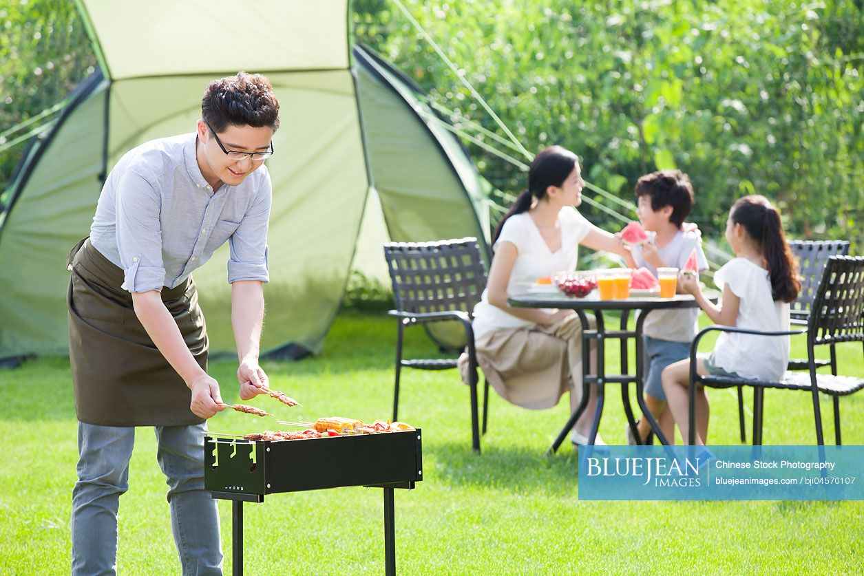 Young Chinese family barbecuing outdoors