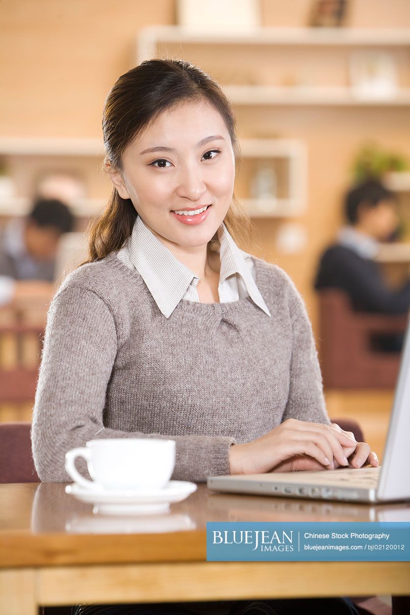 Young Chinese man using laptop at coffee shop