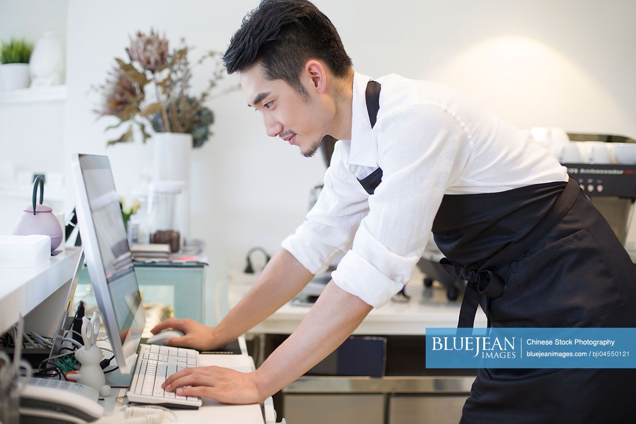 Chinese coffee shop owner using computer