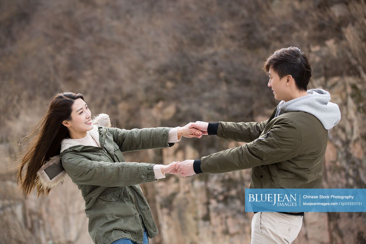 Happy young Chinese couple holding hands spinning