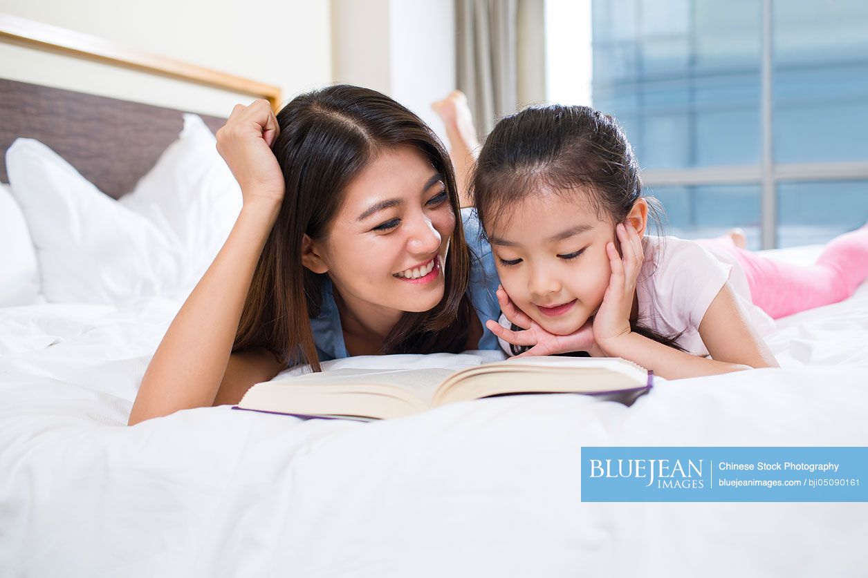 Little Chinese girl reading a book with mother