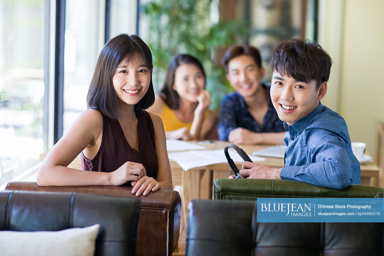Young Chinese friends drinking coffee in cafe