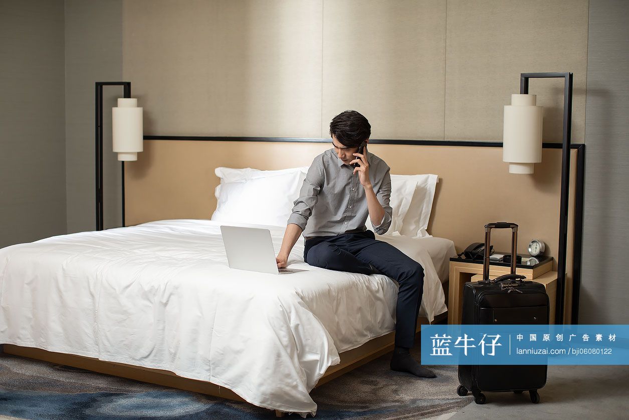年轻商务男士在酒店房间使用手机