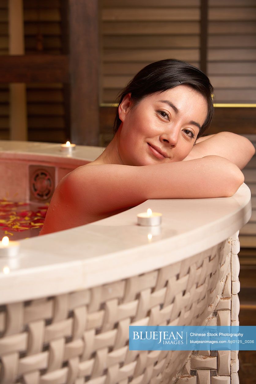 Chinese woman relaxing in a rose petal bath