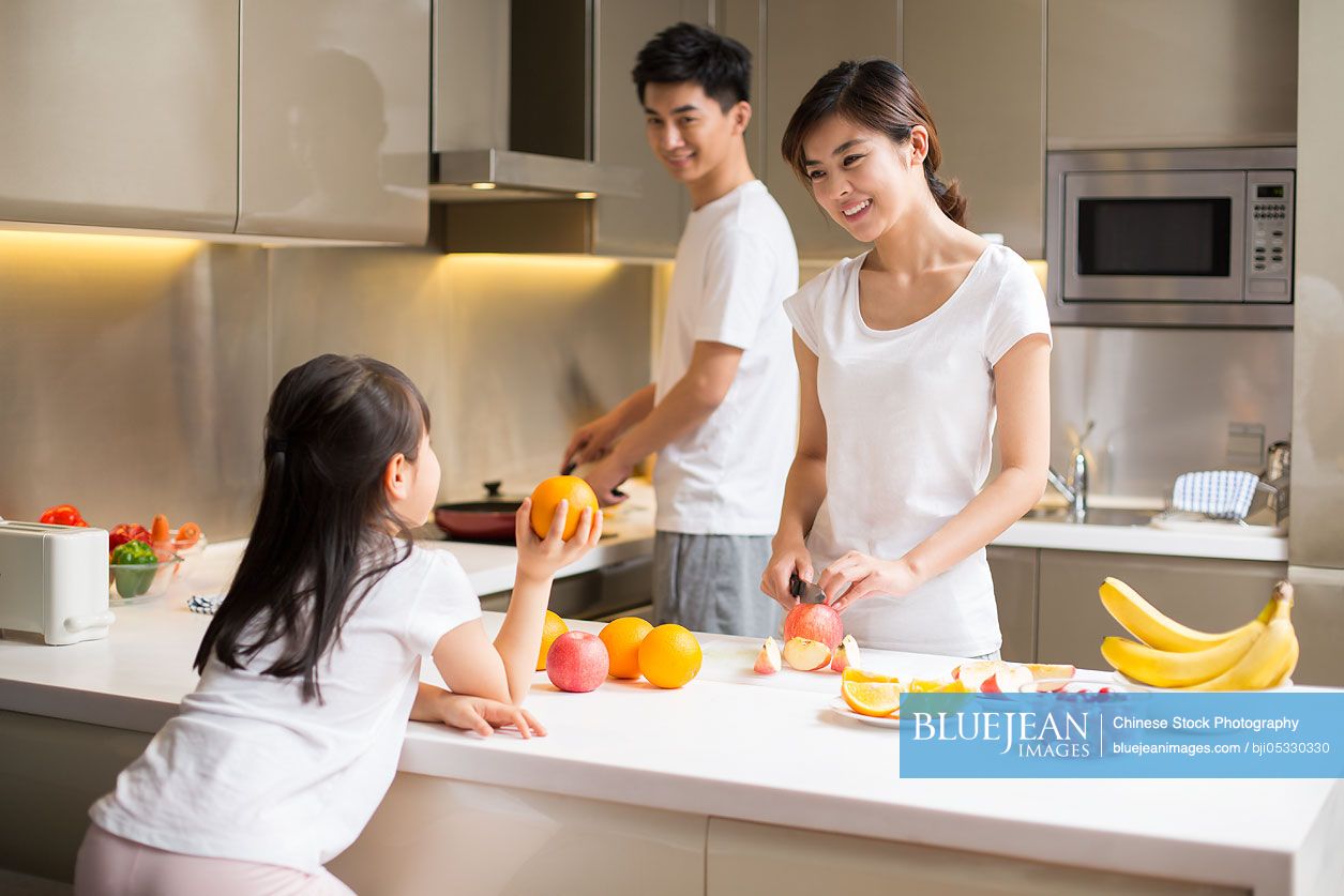 Happy young Chinese family cooking in kitchen