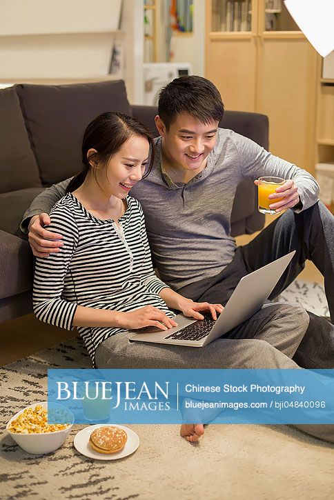 Young Chinese couple using laptop in living room
