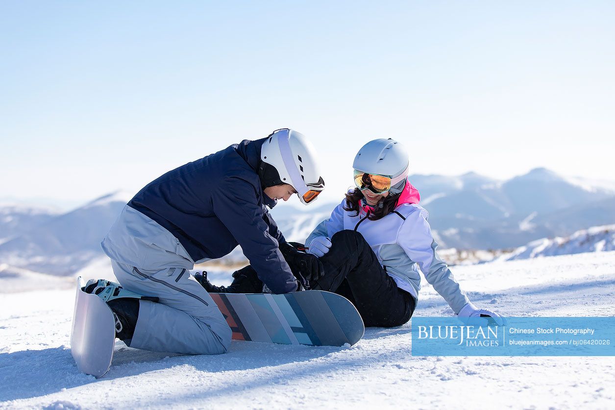 Young Chinese couple with snowboard on the snow