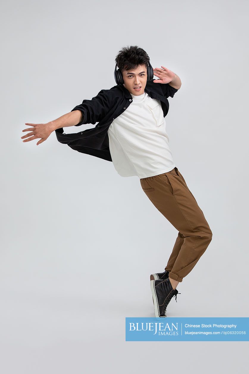 Cool young Chinese man dancing with headphones