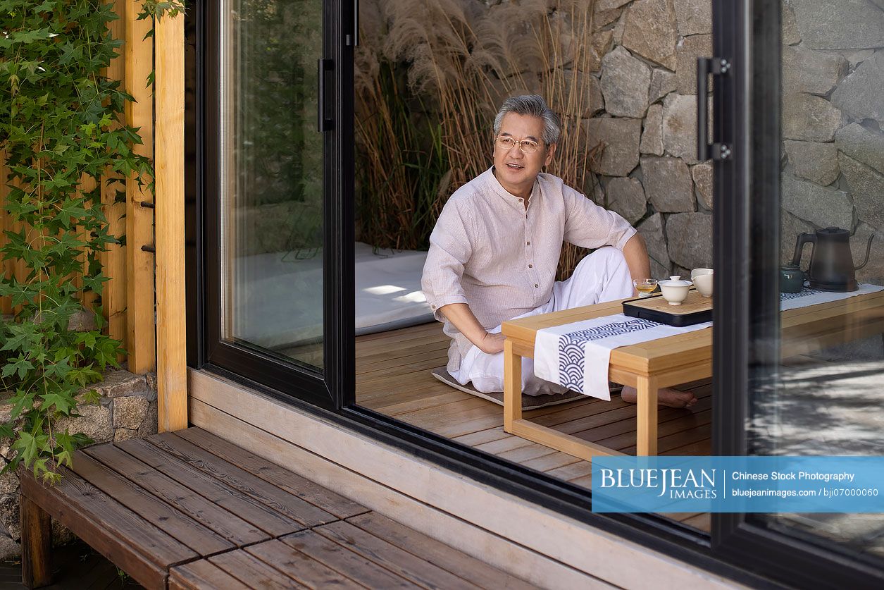 Mature Chinese man drinking tea in tea room