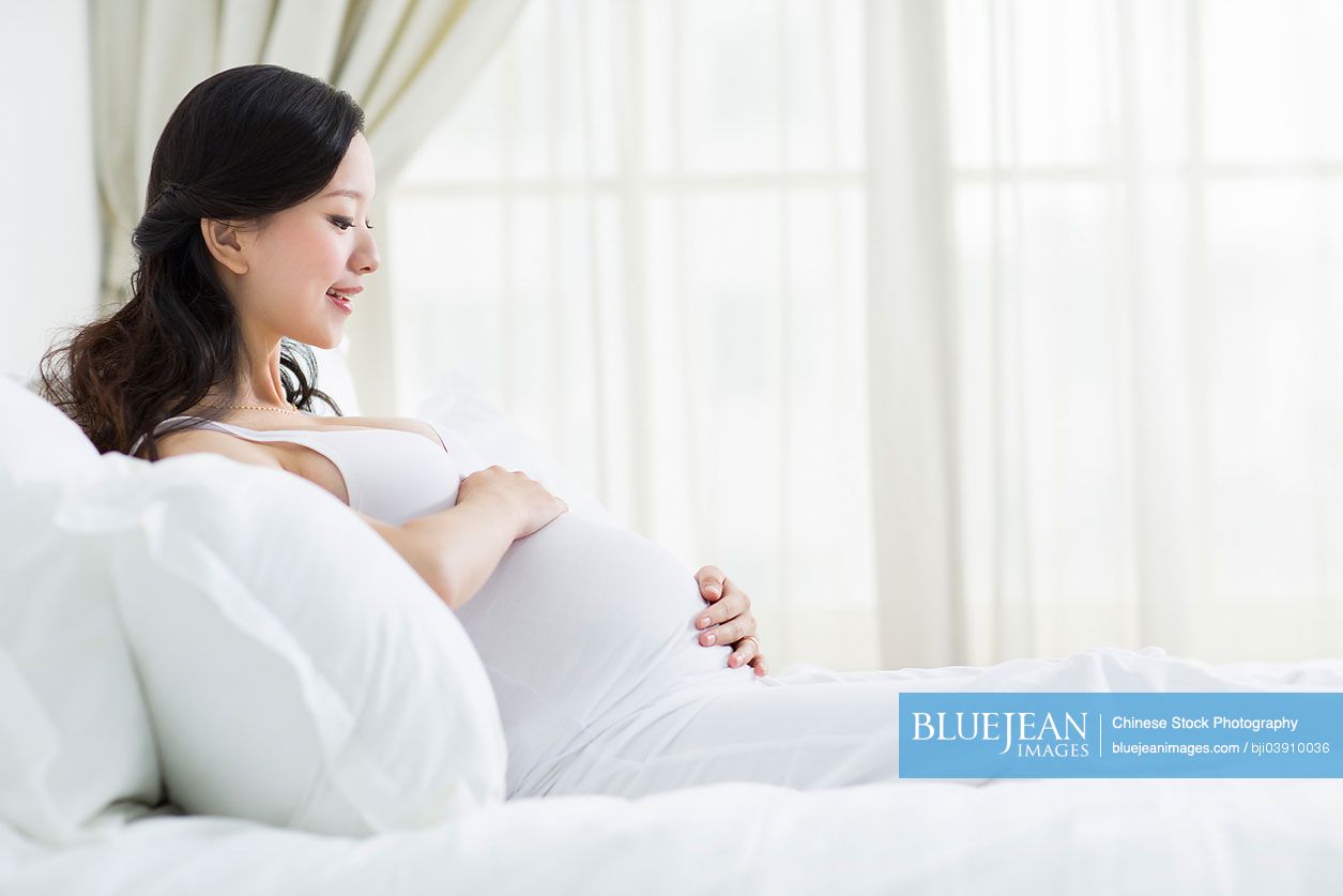 Pregnant Chinese woman resting in bed