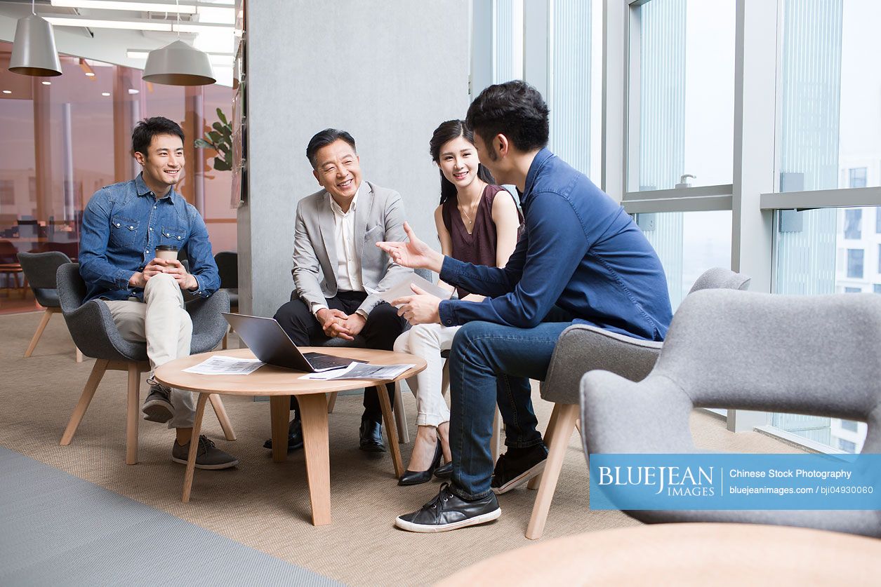 Chinese business people talking in meeting with a laptop