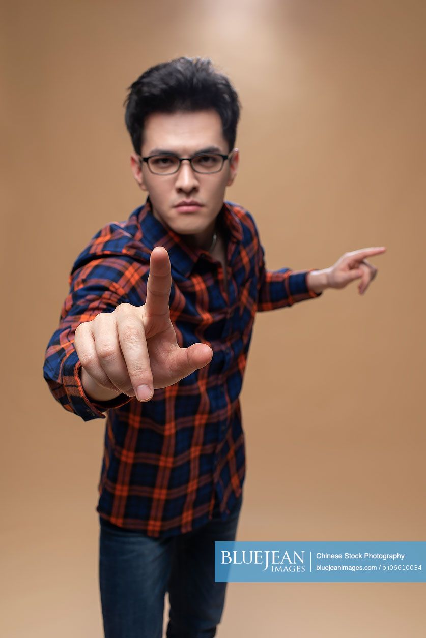 Studio shot of young Chinese man pointing