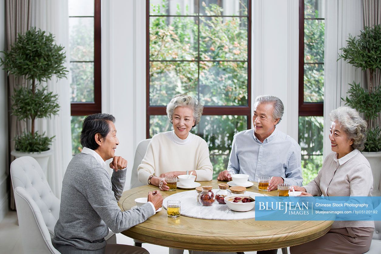 Happy senior Chinese friends eating together