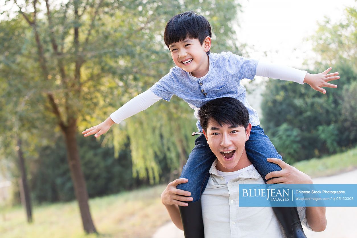 Cheerful young Chinese family playing outdoors