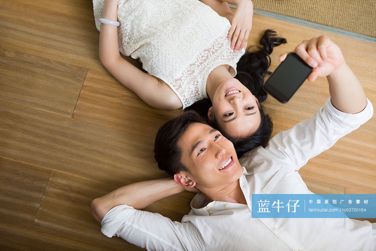 情侣躺在地板上用手机自拍