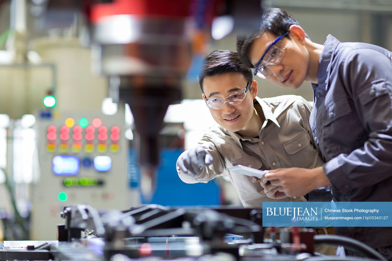 Young Chinese engineers checking machine in the factory