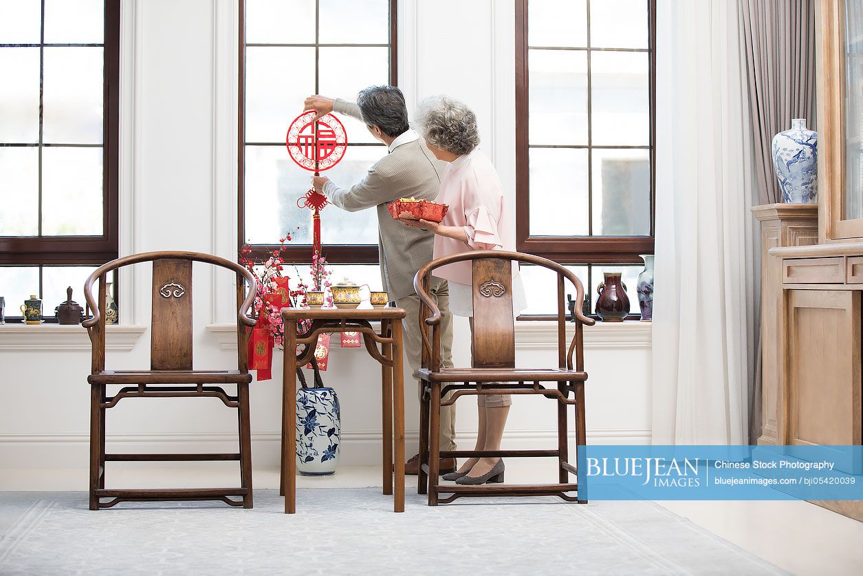 Senior couple decorating their house for Chinese New Year
