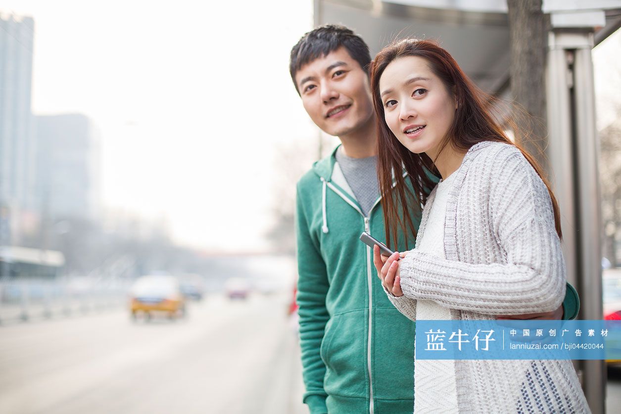 年轻情侣在公交车站等车