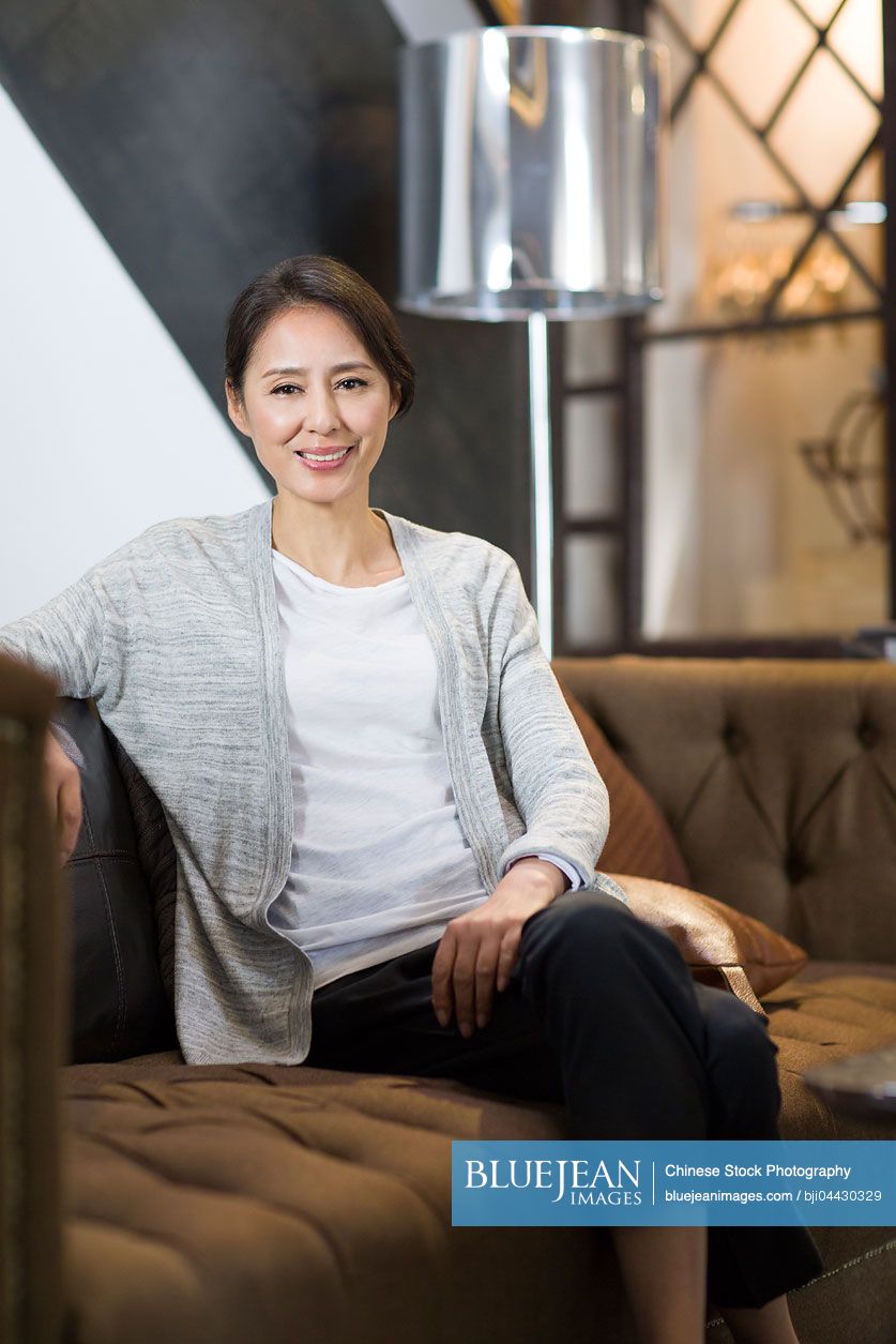 Mature Chinese woman sitting on sofa