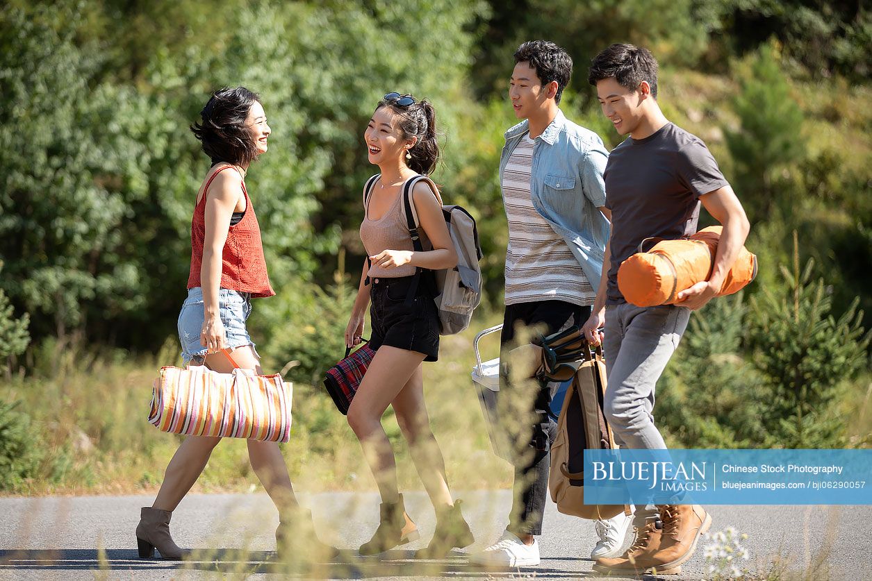 Happy young Chinese friends camping outdoors