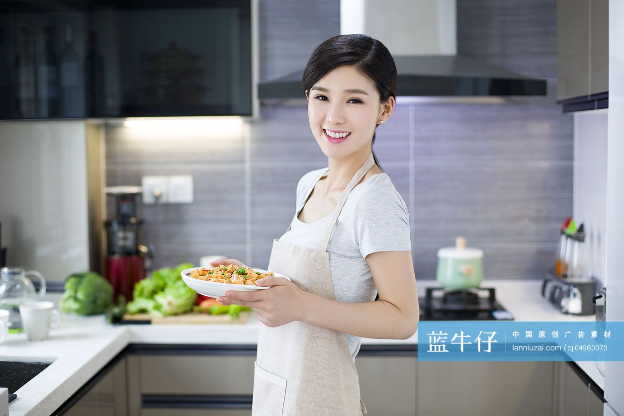 年轻女子在厨房端着一盘菜