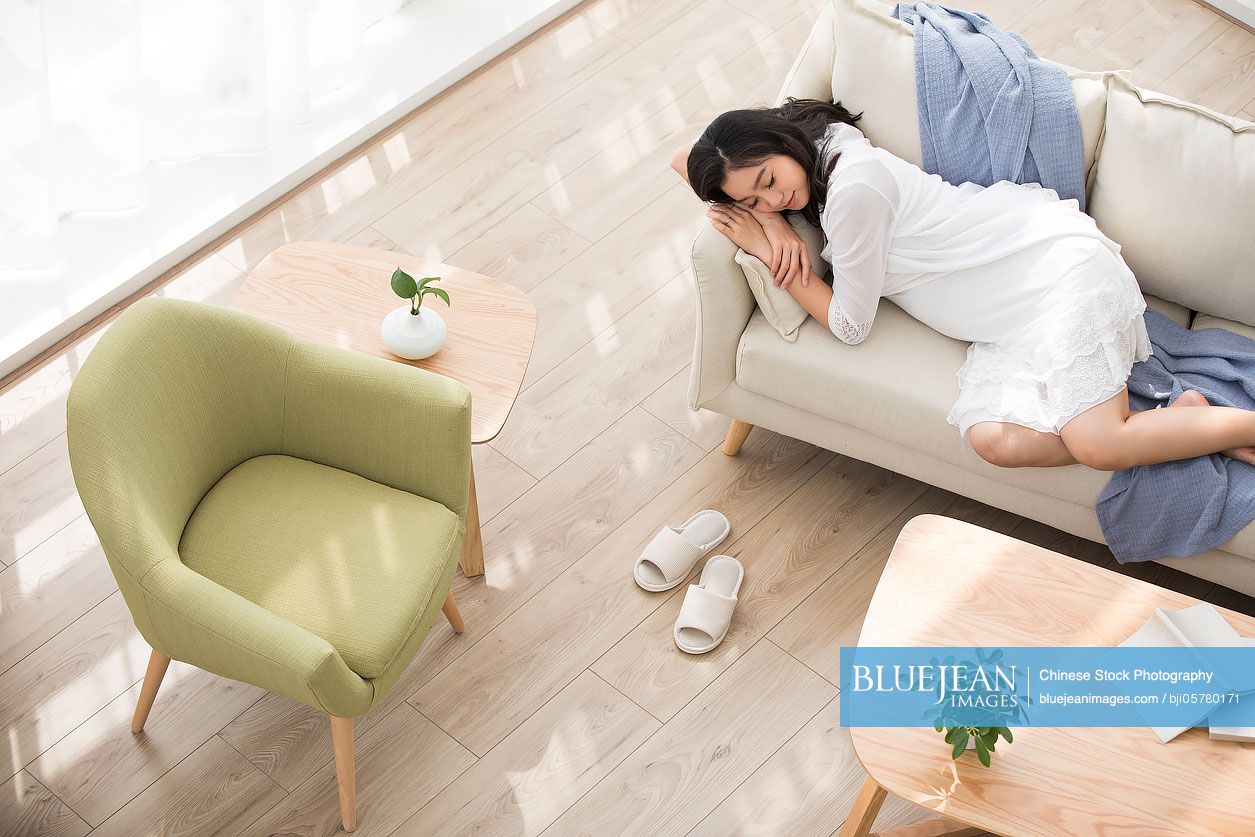 Cheerful Chinese pregnant woman relaxing at home