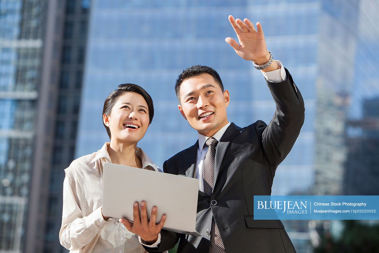 Chinese business coworkers with laptop discussing