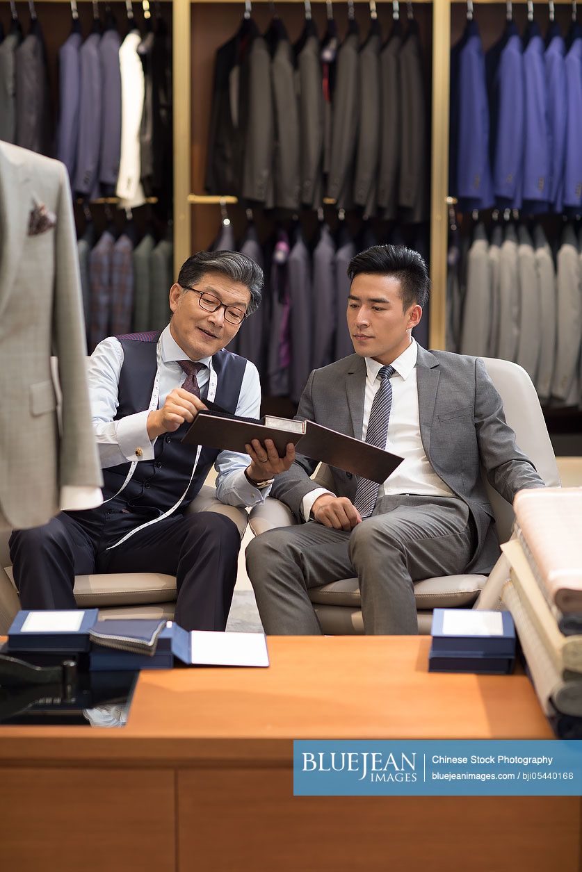 Chinese fashion designer and customer talking in menswear shop