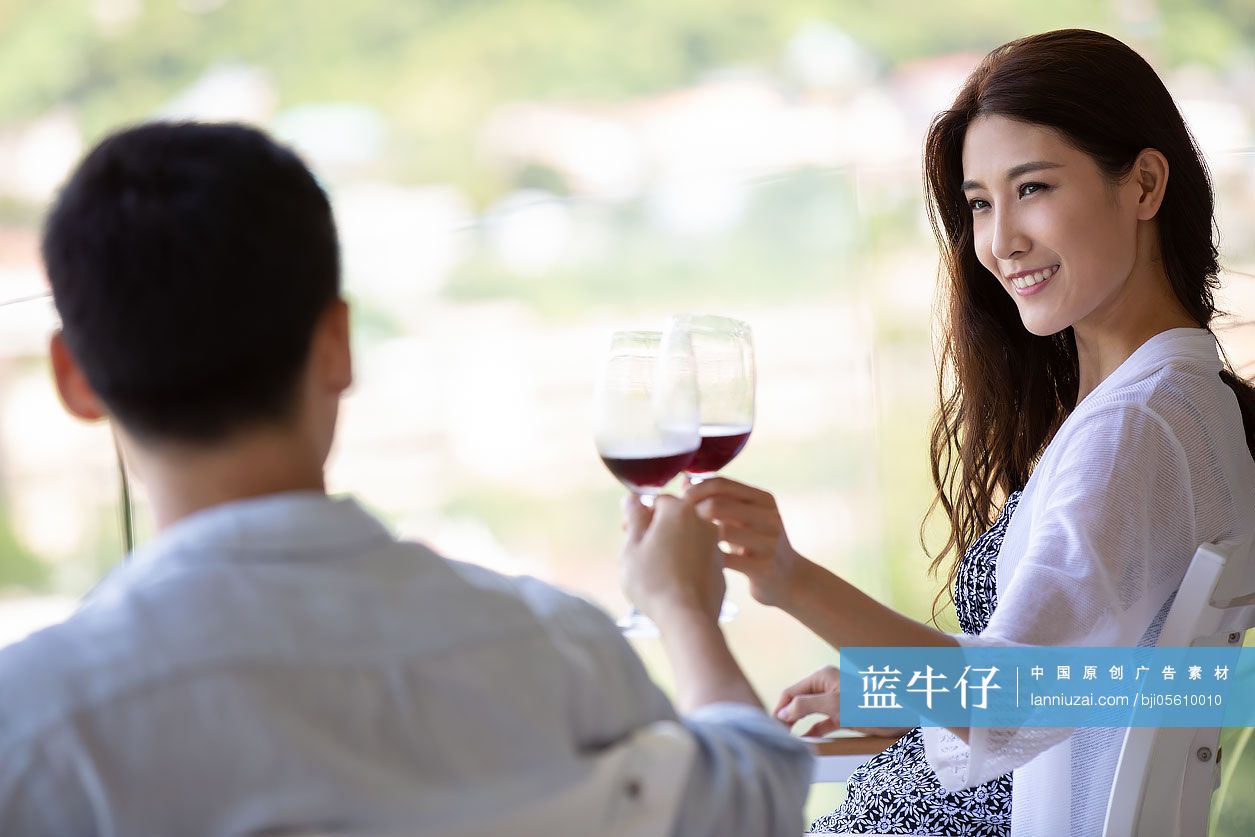 年轻夫妇在露台喝红酒
