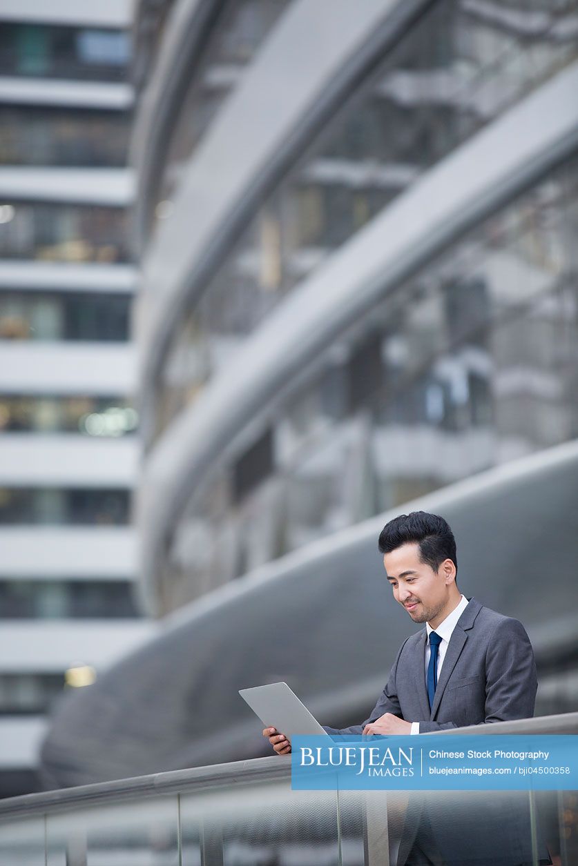 Chinese businessman using laptop outdoors