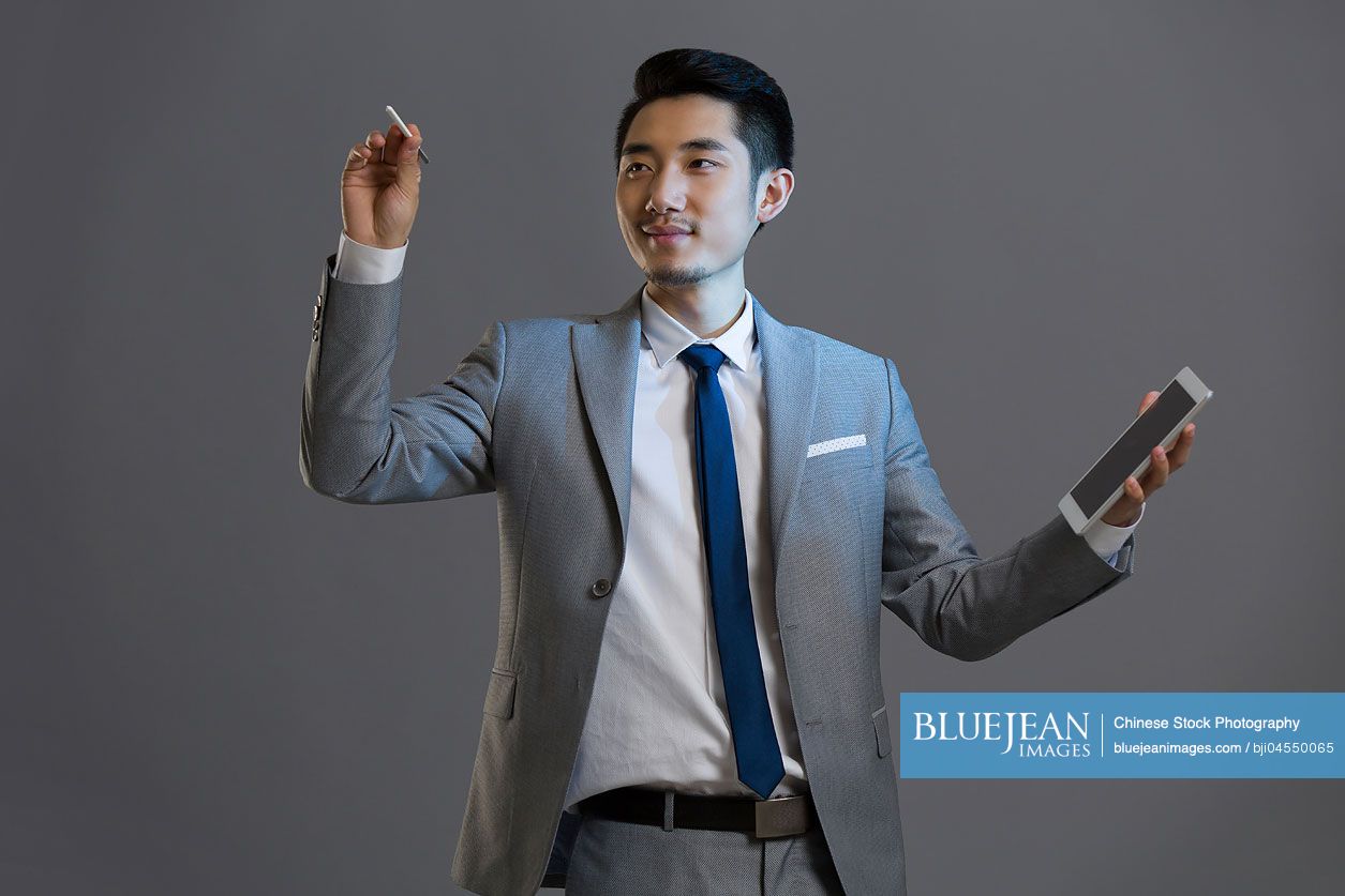 Happy young Chinese businessman using digital tablet