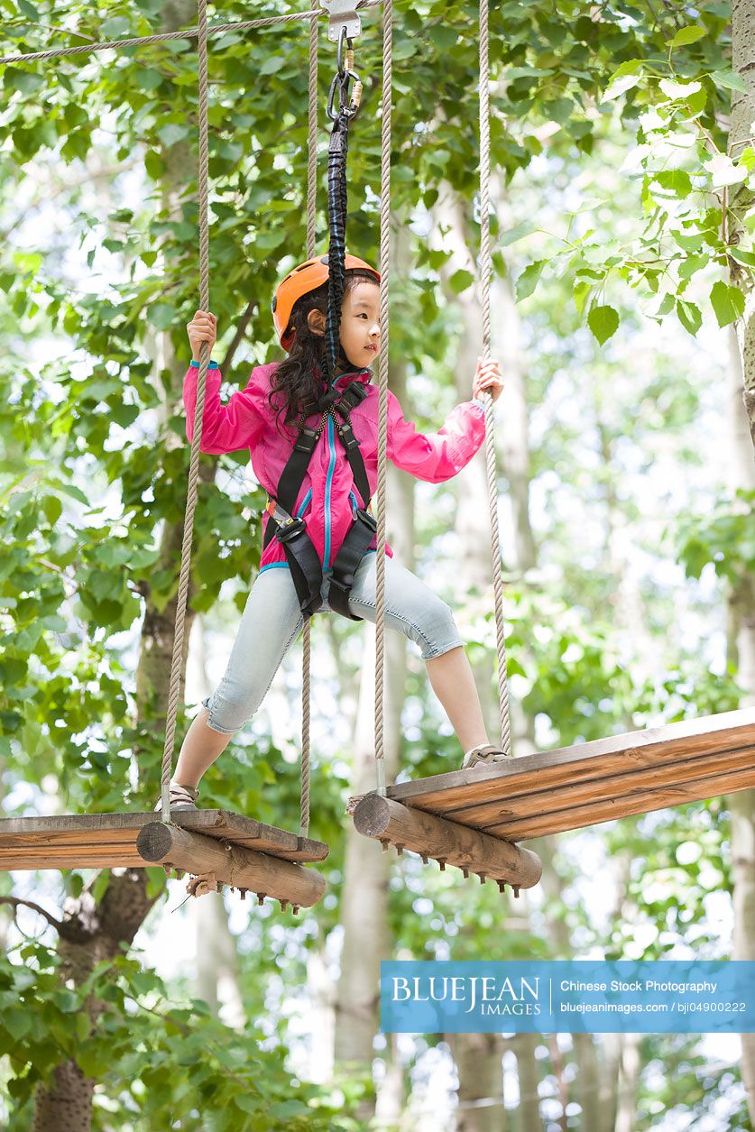 Little Chinese girl playing in tree top adventure park