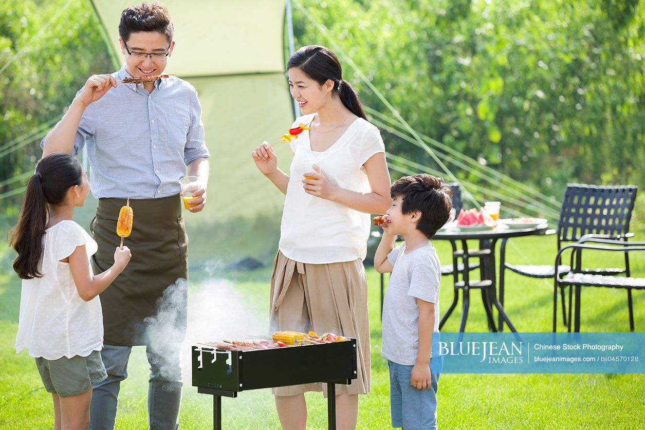 Young Chinese family barbecuing outdoors